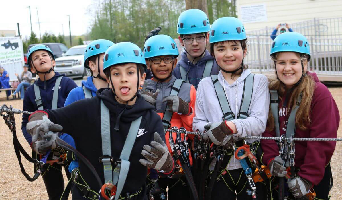 Kids in helmets and harnesses on a ropes course